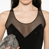 Black maxi dress with sheer mesh panel detail at neckline and racerback design, styled with silver clutch and crystal earrings — Norma Kamali | Endless UAE