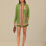 Woman wearing green patterned button-up romper with striped trim and brown accessories — Farm Rio | Endless UAE