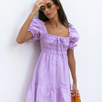 Lilac linen mini dress with puff sleeves and smocked bodice, styled with sunglasses and orange Fanta bottles — Else Adelia | Endless UAE
