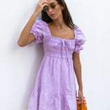 Lilac linen mini dress with puff sleeves and smocked bodice, styled with sunglasses and orange Fanta bottles — Else Adelia | Endless UAE
