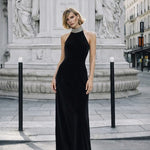Woman wearing black halter neck velvet evening dress standing in front of historic building — COPURS | Endless UAE