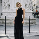 Woman wearing black halter neck velvet evening dress standing in front of historic building — COPURS | Endless UAE