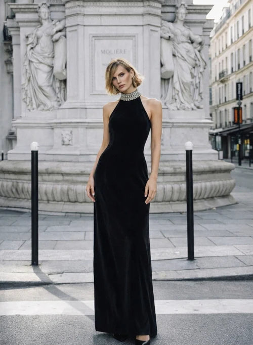 Woman wearing black halter neck velvet evening dress standing in front of historic building — COPURS | Endless UAE
