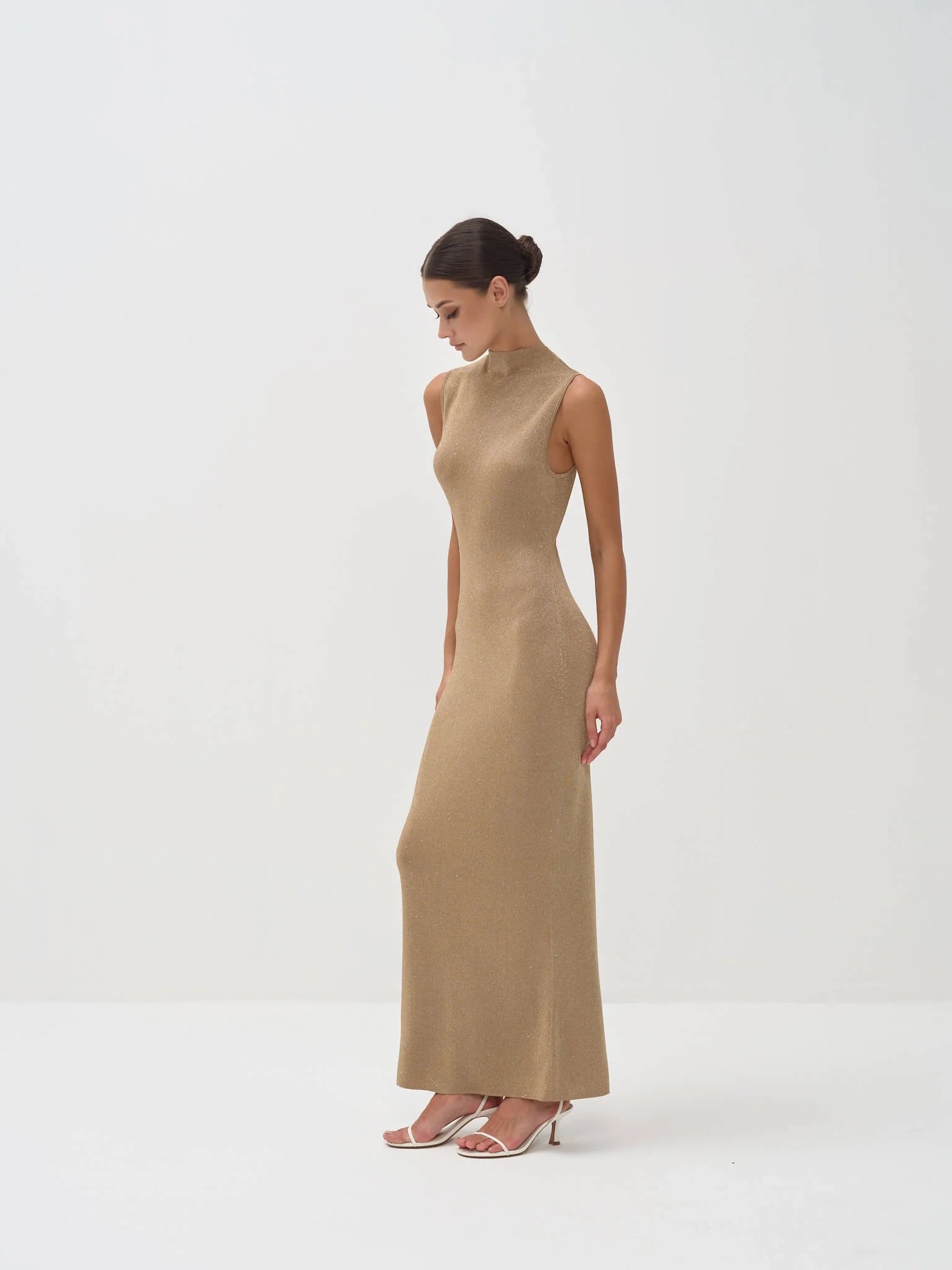 Elegant sleeveless gold maxi dress with mock neck, fitted silhouette, worn with strappy heels — Nora The Label | Endless UAE