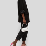 White quilted mini shoulder bag with silver hardware held up against neutral background — By Far | Endless UAE