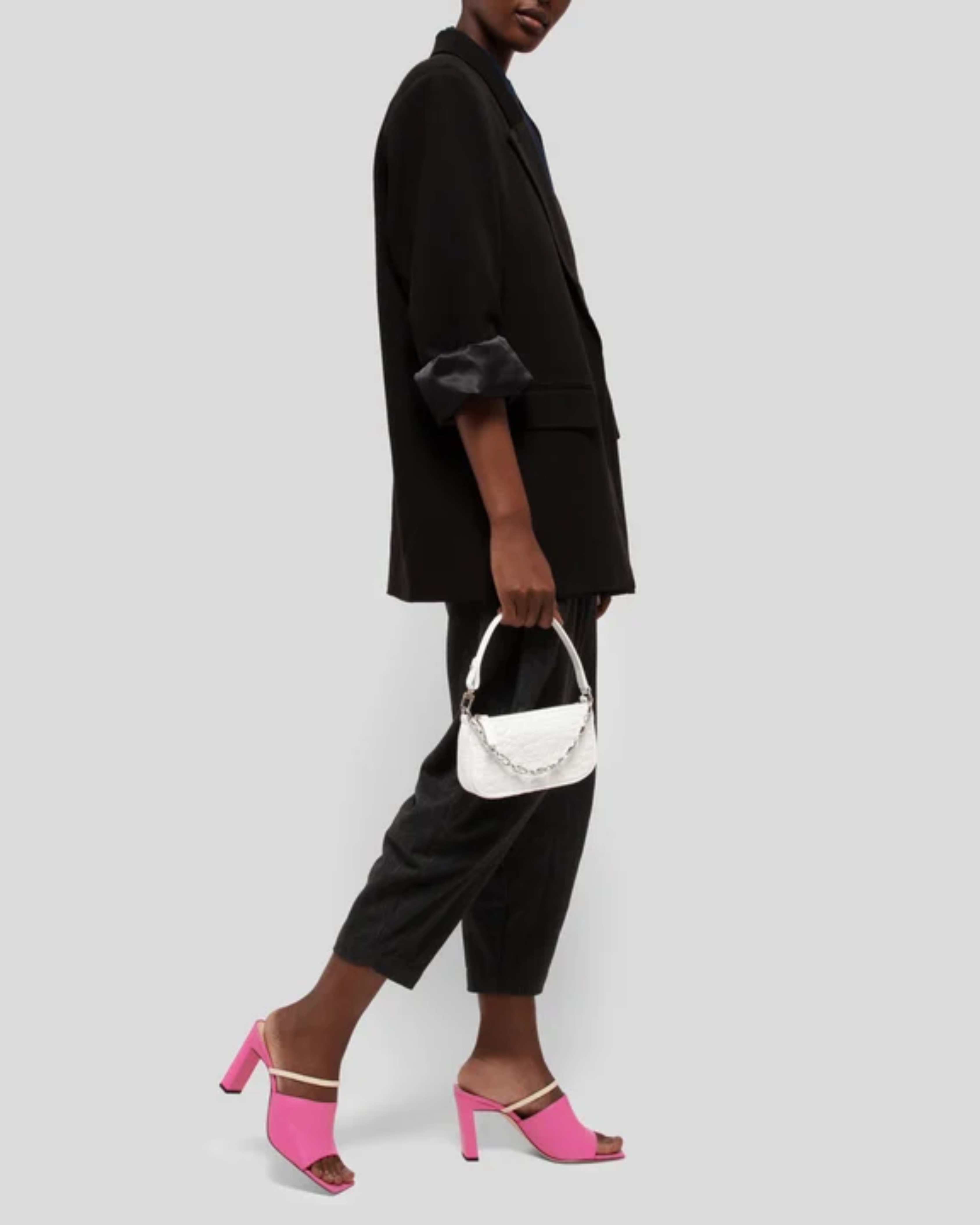 White quilted mini shoulder bag with silver hardware held up against neutral background — By Far | Endless UAE