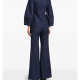 Woman wearing indigo denim jacket and flared jeans with white clutch — Florence & Fortitude | Endless UAE