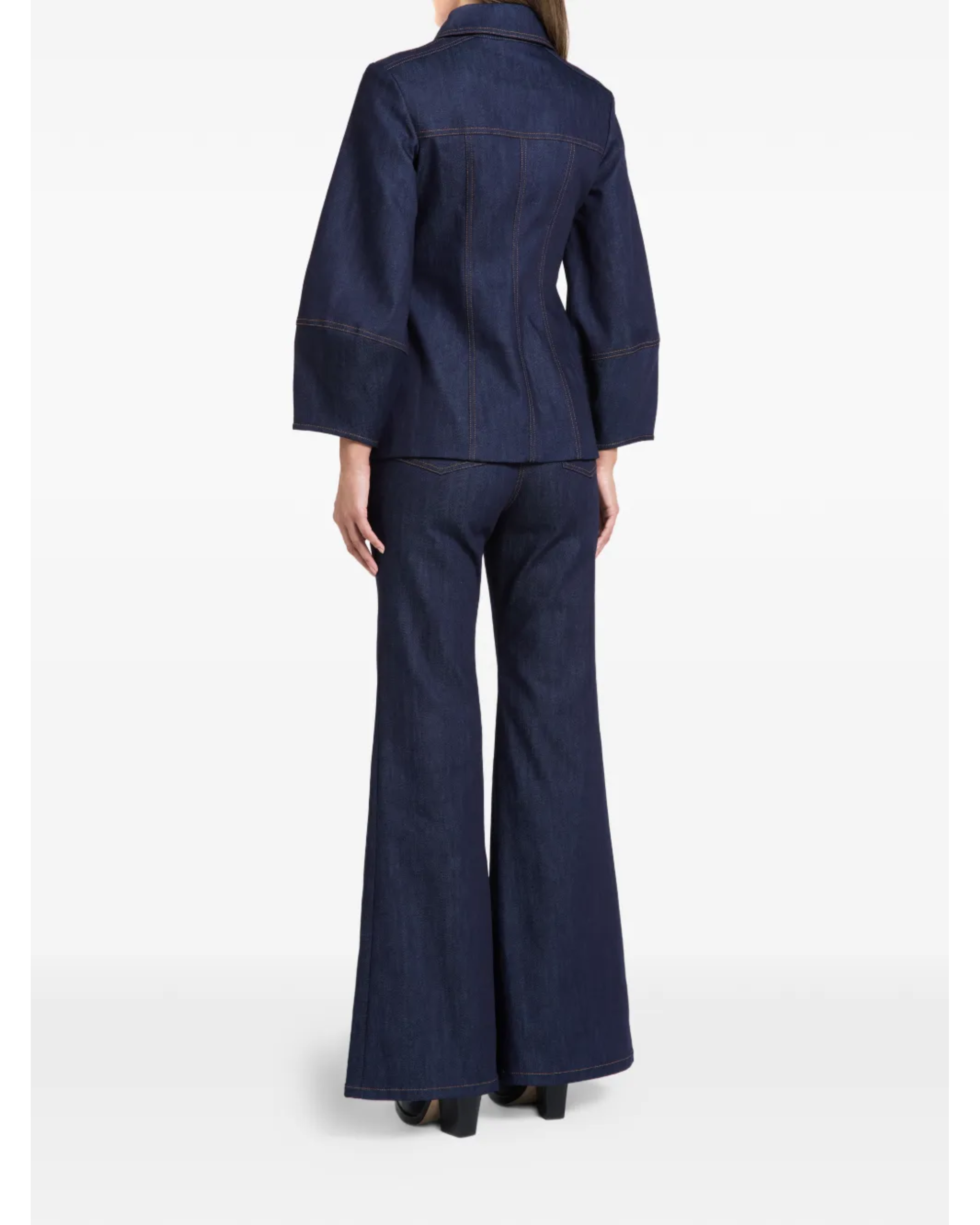 Woman wearing indigo denim jacket and flared jeans with white clutch — Florence & Fortitude | Endless UAE