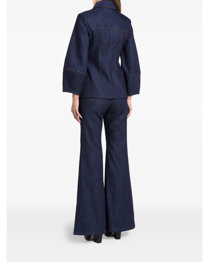 Woman wearing indigo denim jacket and flared jeans with white clutch — Florence & Fortitude | Endless UAE