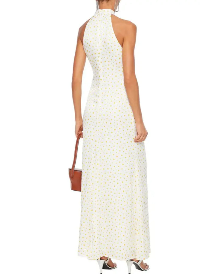 Woman wearing white Coastal Daisy Maxi Dress with yellow floral print and halter neckline — Staud | Endless UAE