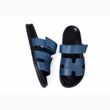 Black leather slide sandals with cutout straps displayed on orange box — Hermès | Endless UAE