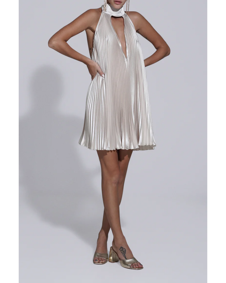 Woman wearing champagne pleated halterneck mini dress with deep V-neckline and metallic heeled sandals — L'IDÉE | Endless UAE