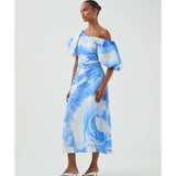 Woman wearing blue and white abstract print Cadence Ruched Midi Dress with puffed sleeves and white slides — Aje | Endless UAE