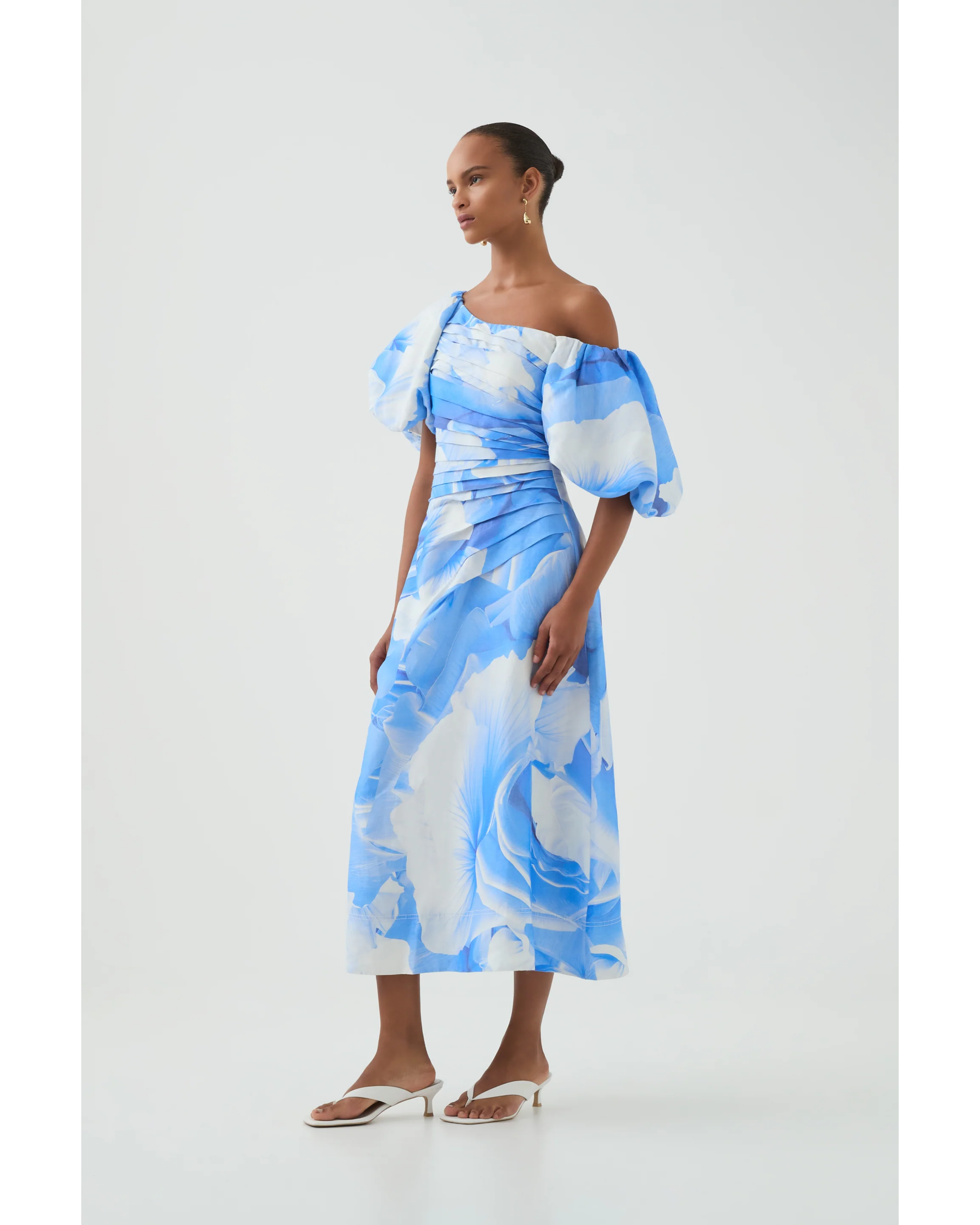 Woman wearing blue and white abstract print Cadence Ruched Midi Dress with puffed sleeves and white slides — Aje | Endless UAE