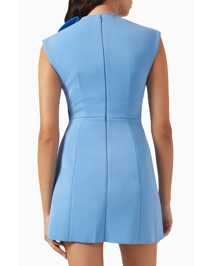 Woman wearing a light blue sleeveless mini dress with ruffled shoulder detail, white shoulder bag, and strappy heels — Acler | Endless UAE