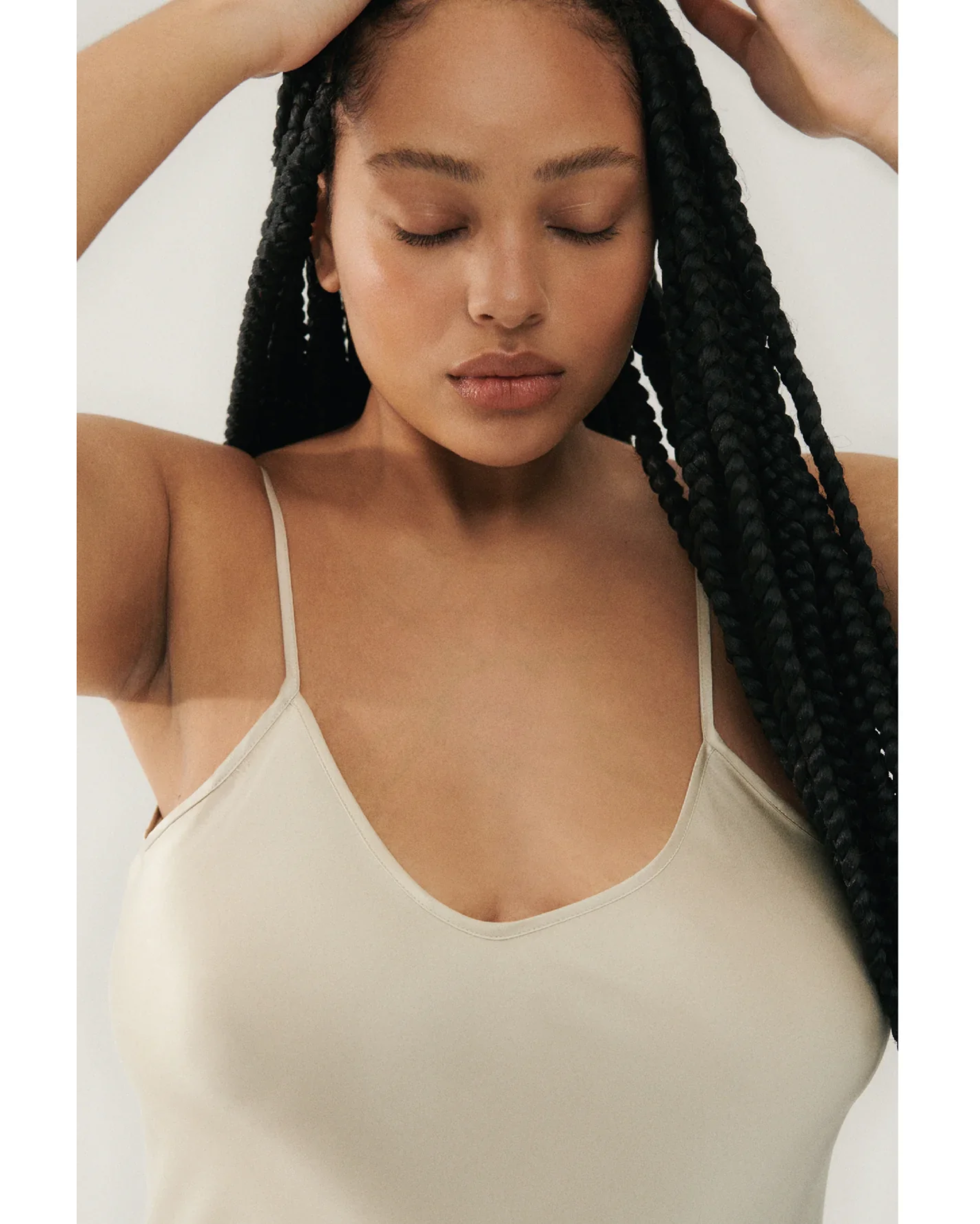 Woman wearing cream spaghetti strap slip dress with black strappy heels — Silk Laundry | Endless UAE