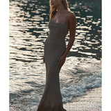 Woman in black patterned maxi dress standing by sparkling ocean water at golden hour — Monday Swimwear | Endless UAE