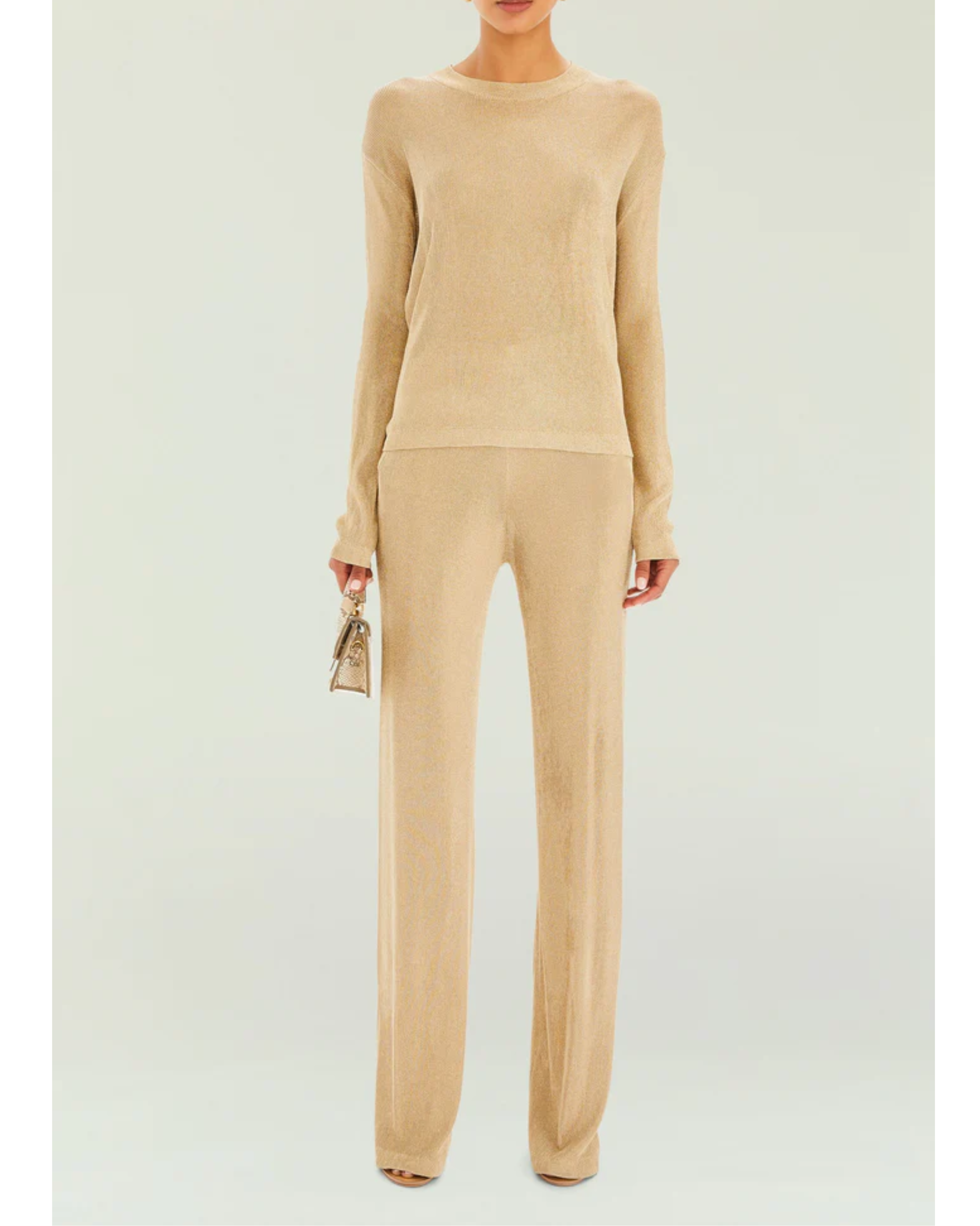 Woman wearing a beige metallic knit top and matching trousers holding a small handbag — SER.O.YA | Endless UAE