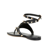 Black leather thong sandals with gold pyramid studs and double ankle wrap straps — Valentino Garavani | Endless UAE
