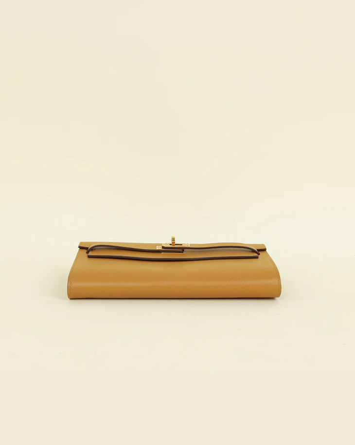 Tan leather Hermes Kelly To Go Evercolor wallet with gold-tone clasp closure and structured silhouette on beige background — Hermes | Endless UAE