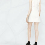 Woman wearing white sleeveless mini dress with cut-out detail, shown from back, paired with black platform shoes — Courrèges | Endless UAE