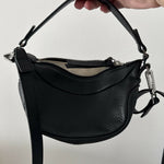 Black leather mini shoulder bag with textured finish held open to show interior — By Far | Endless UAE