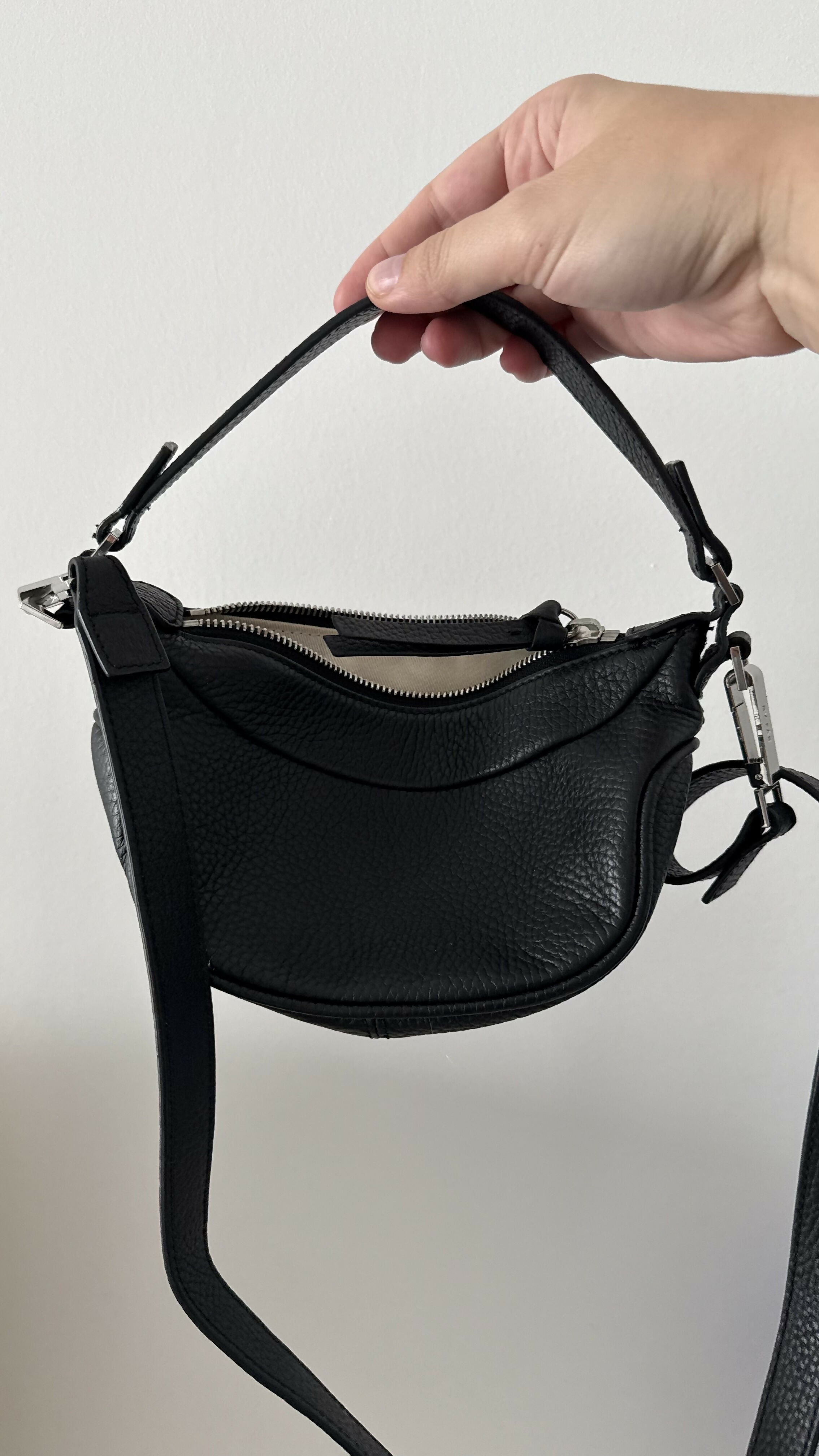 Black leather mini shoulder bag with textured finish held open to show interior — By Far | Endless UAE