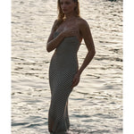 Woman in patterned strapless maxi dress standing in shallow ocean water at sunset — Monday Swimwear | Endless UAE