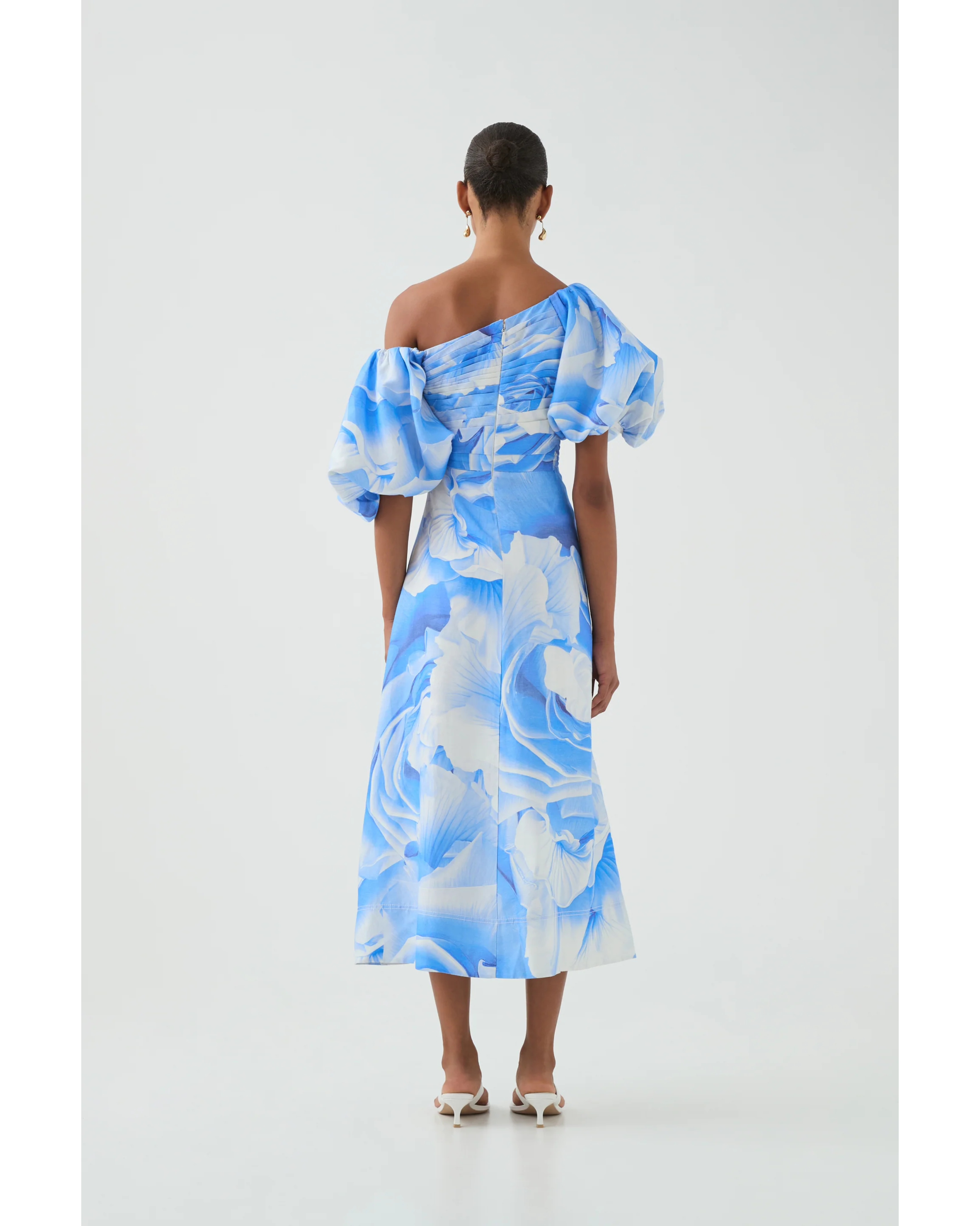 Woman wearing blue and white abstract print Cadence Ruched Midi Dress with puffed sleeves and white slides — Aje | Endless UAE