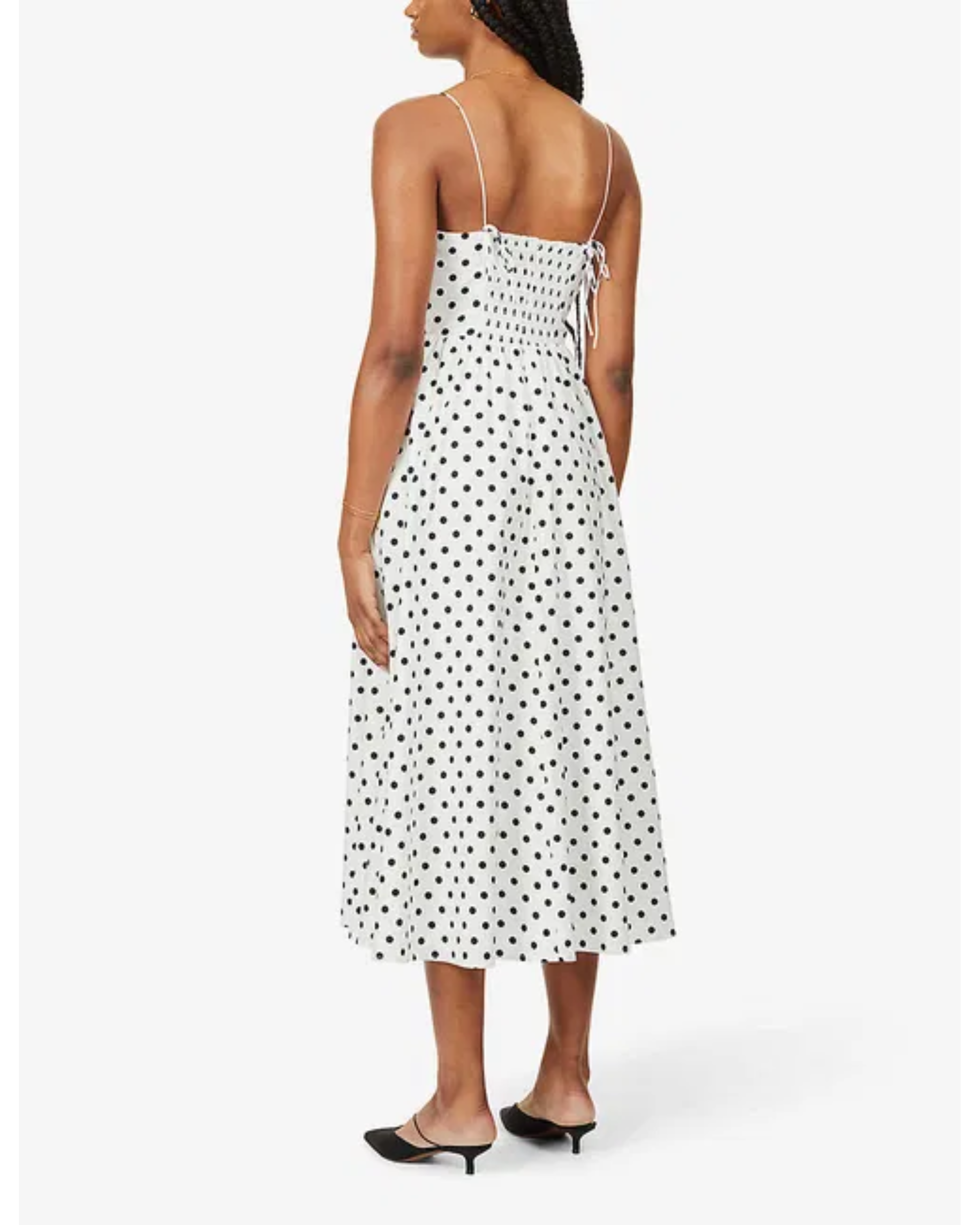 Woman wearing white polka-dot spaghetti-strap midi dress with smocked back and black heeled mules, back view — Reformation | Endless UAE