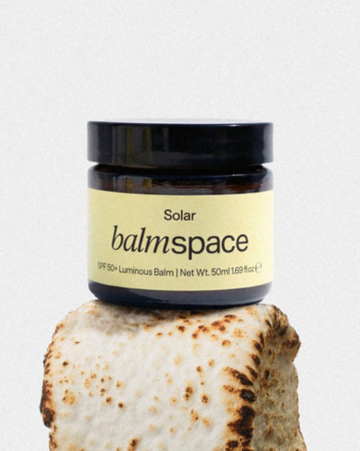 SPF 50+ Face Luminous Balm in dark amber jar with yellow label displayed on textured stone — Balm Space | Endless UAE