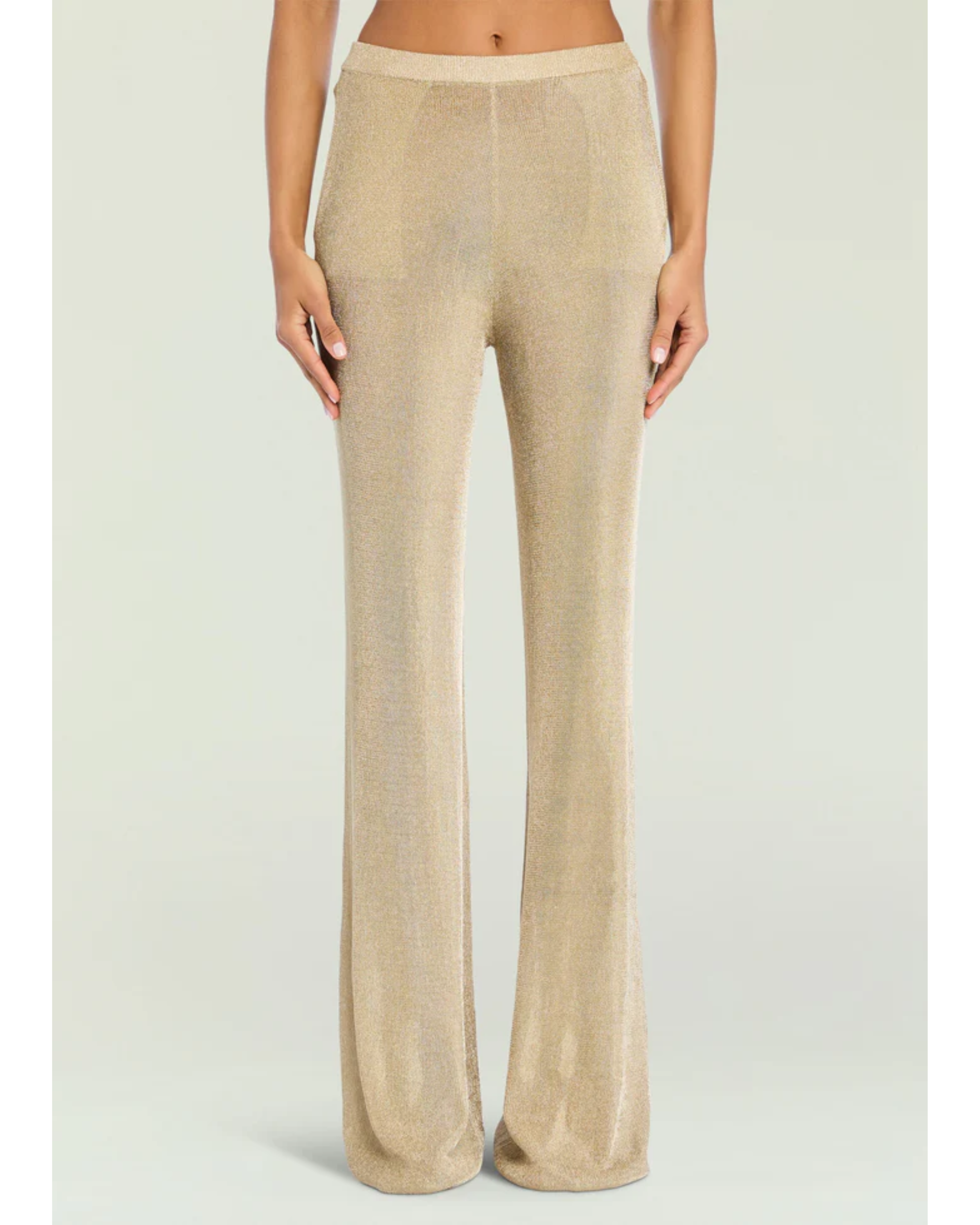 Woman wearing a beige metallic knit top and matching trousers holding a small handbag — SER.O.YA | Endless UAE