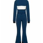 Woman wearing navy and white colorblocked ski jumpsuit with belt and black boots — Cordova | Endless UAE