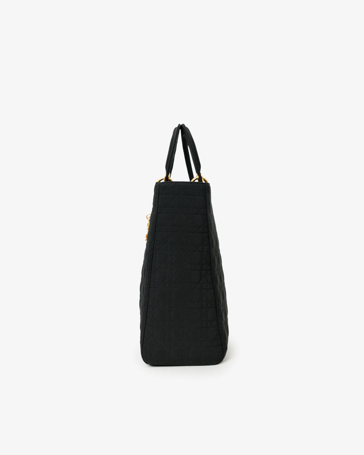 Black cannage quilted nylon tote bag with dual handles and gold hardware, side profile view — Dior | Endless UAE