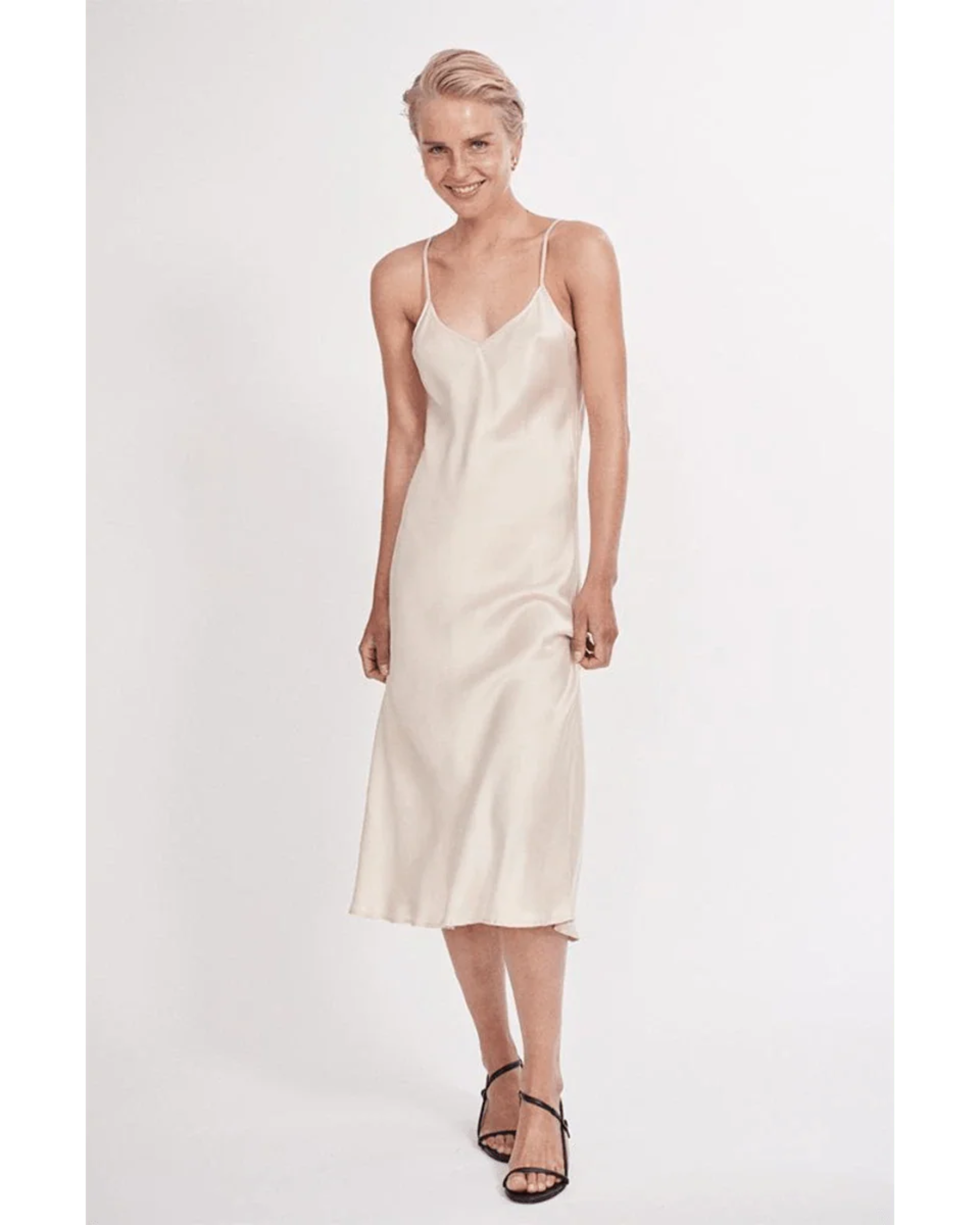 Woman wearing cream spaghetti strap slip dress with black strappy heels — Silk Laundry | Endless UAE