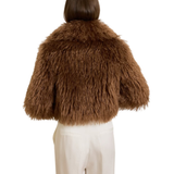 Woman wearing camel-colored fur stole jacket over cream top and pants with burgundy shoes — Madame Magdalena | Endless UAE