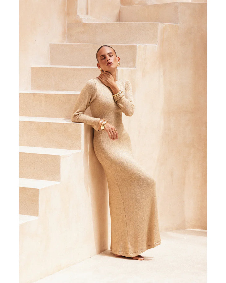 Woman wearing beige long-sleeve maxi dress standing in minimalist architectural setting — Miharo | Endless UAE