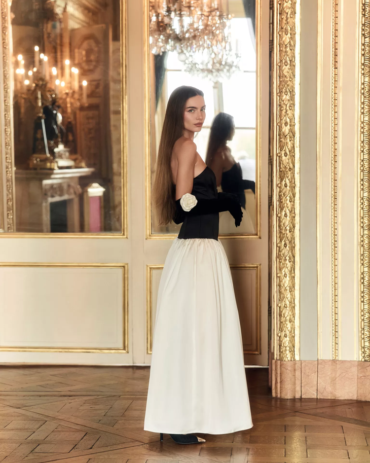 Woman wearing black and white off-shoulder Parisienne Maxi Dress in ornate palace room — Lichi | Endless UAE