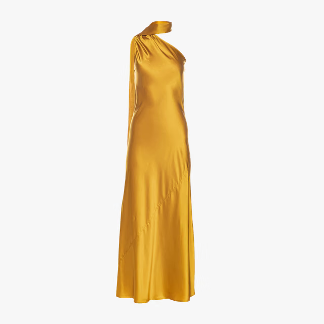 Woman wearing golden yellow silk slip dress standing on rocks by the sea — Vasiliki | Endless UAE