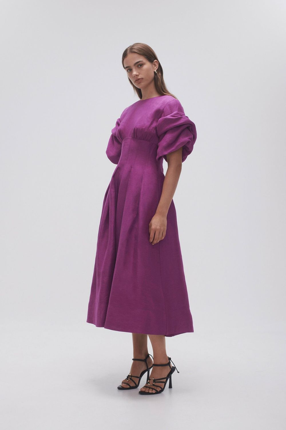 Woman wearing Adelie Puff Sleeve Midi Dress in plum with black strappy sandals — Aje | Endless UAE