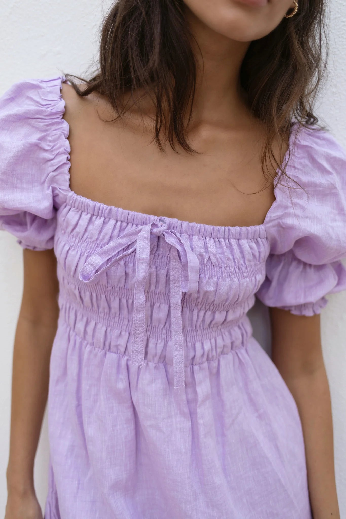Lilac linen mini dress with puff sleeves and smocked bodice, styled with sunglasses and orange Fanta bottles — Else Adelia | Endless UAE
