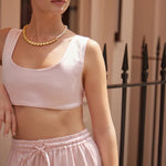 Woman wearing white sculpted bralette with cat-eye sunglasses and gold necklace outdoors — By Keara | Endless UAE