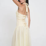 Elegant pale yellow satin maxi dress with halter neck ties, corset-style lacing, and flowing drop-waist skirt — Vivienne Collection | Endless UAE