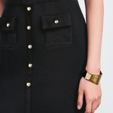 Black knitted mini skirt with silver button front detail and patch pockets, styled with gold cuff bracelet — Claudie Pierlot | Endless UAE