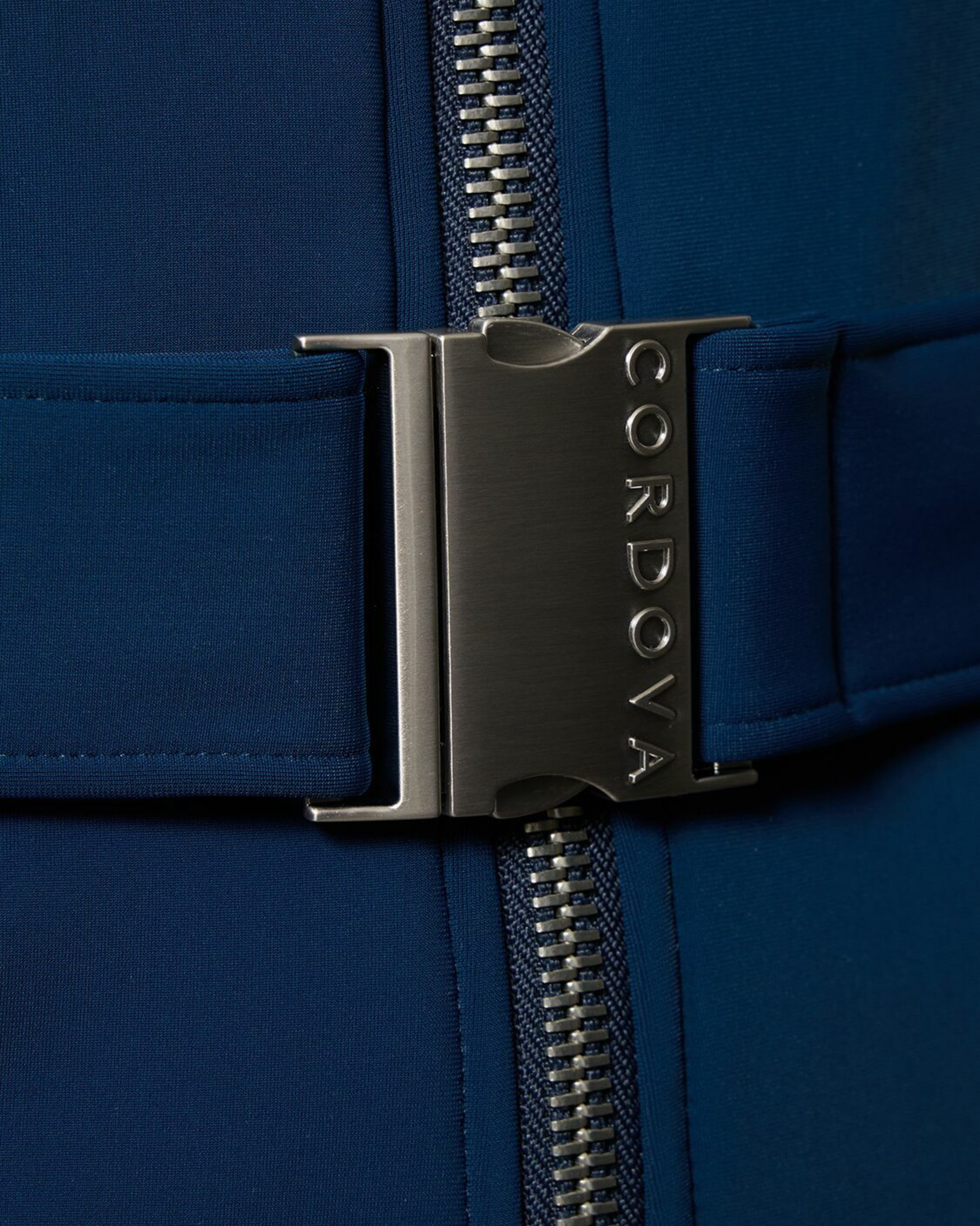 Woman wearing navy and white colorblocked ski jumpsuit with belt and black boots — Cordova | Endless UAE