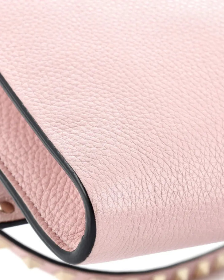 Pink pebbled leather Rockstud crossbody bag with black trim and gold hardware closeup — Valentino Garavani | Endless UAE