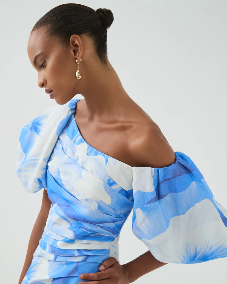 Woman wearing blue and white abstract print Cadence Ruched Midi Dress with puffed sleeves and white slides — Aje | Endless UAE