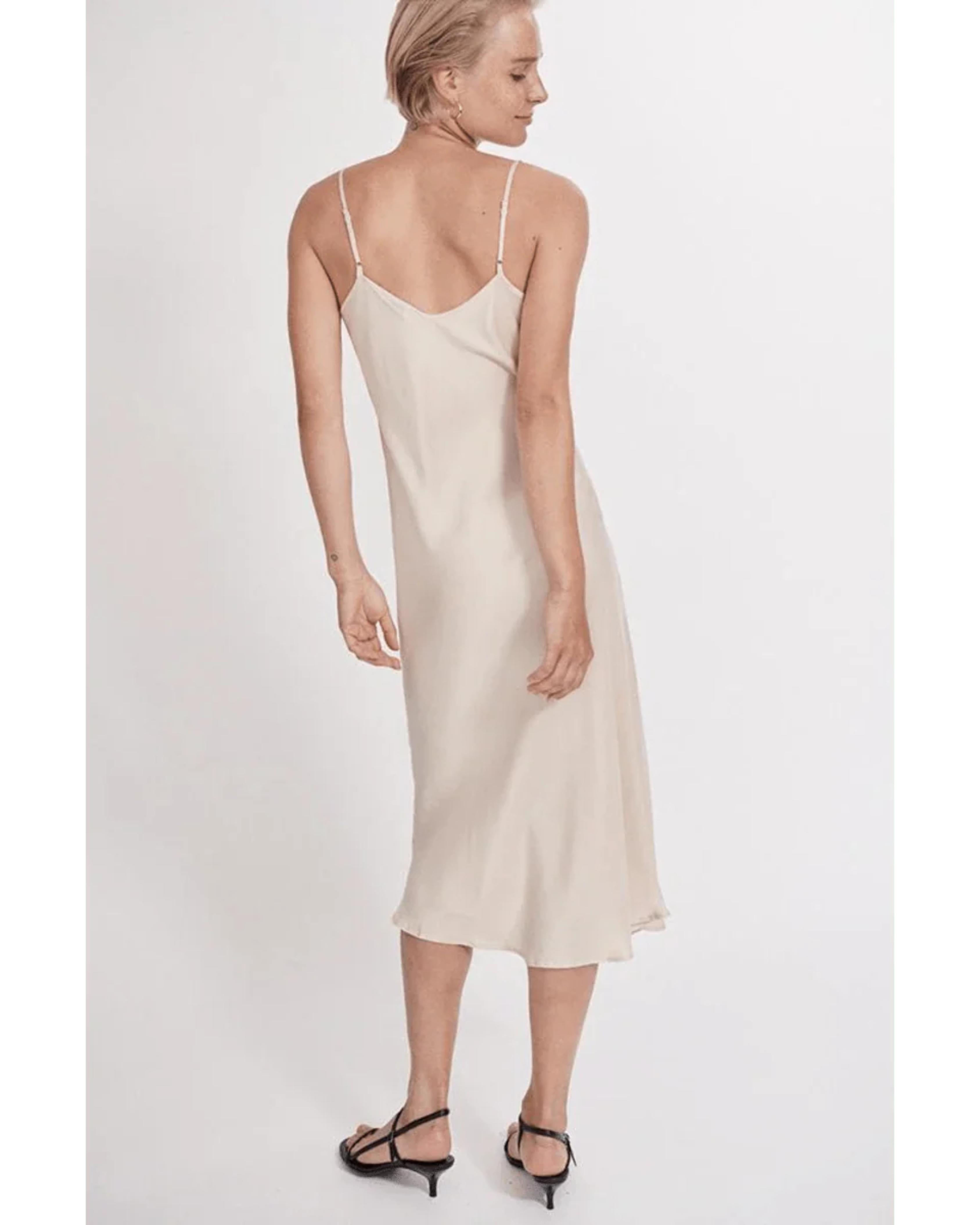Woman wearing cream spaghetti strap slip dress with black strappy heels — Silk Laundry | Endless UAE