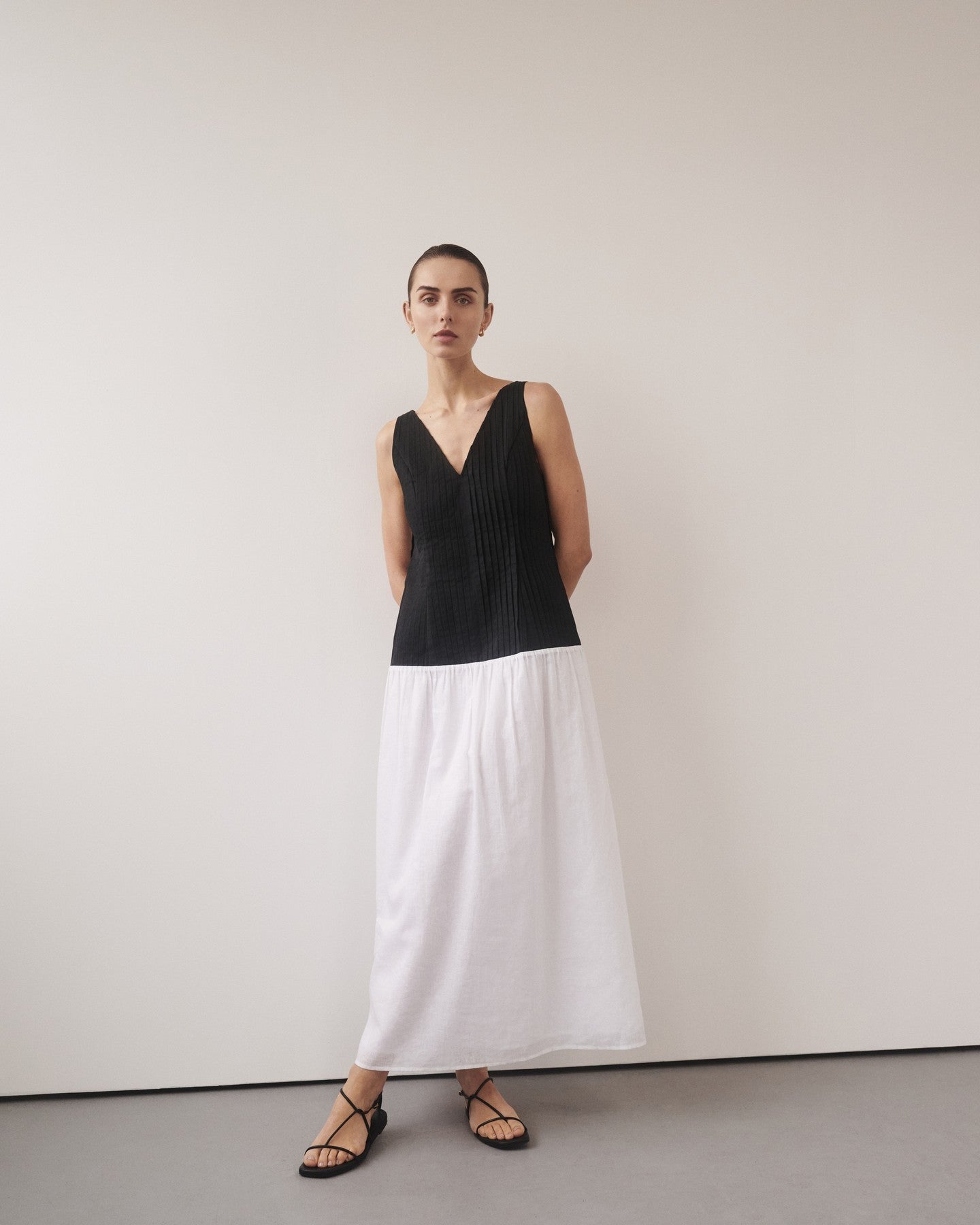 Woman wearing black and white color-block midi dress with V-neckline and black strappy sandals — DISSH | Endless UAE