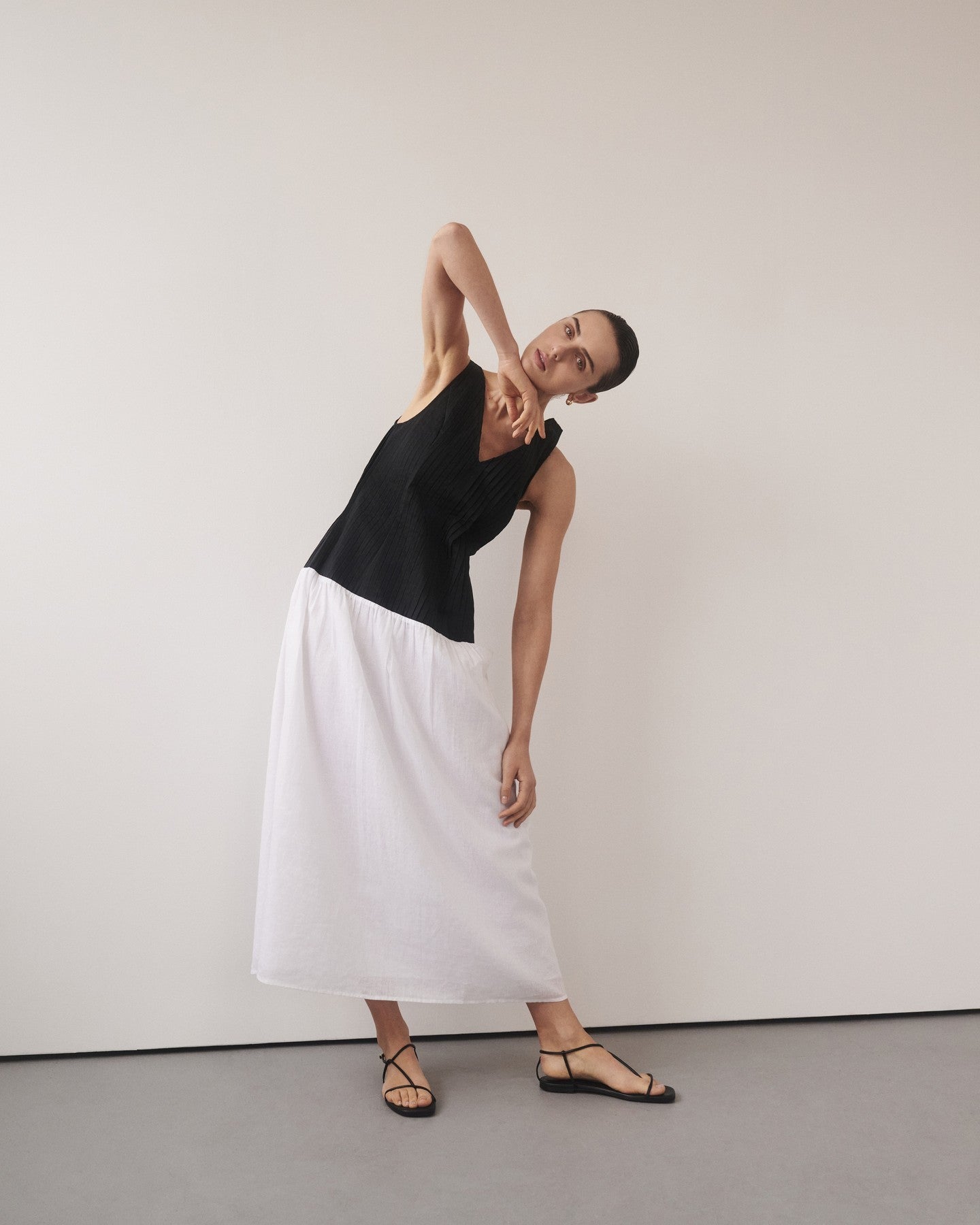 Woman wearing black and white color-block midi dress with V-neckline and black strappy sandals — DISSH | Endless UAE